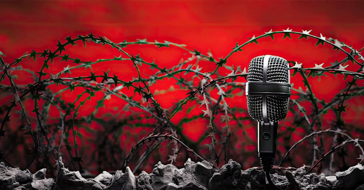 Microphone behind barbed wire with a red sunset background, symbolizing censorship and freedom of speech, related to America Out Loud news and conservative news topics.