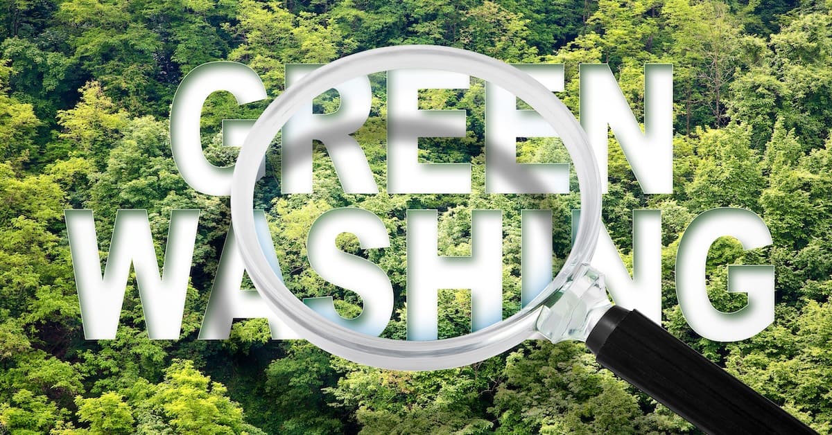 Alert to Greenwashing – concept with text against a forest and trees and magnifying glass