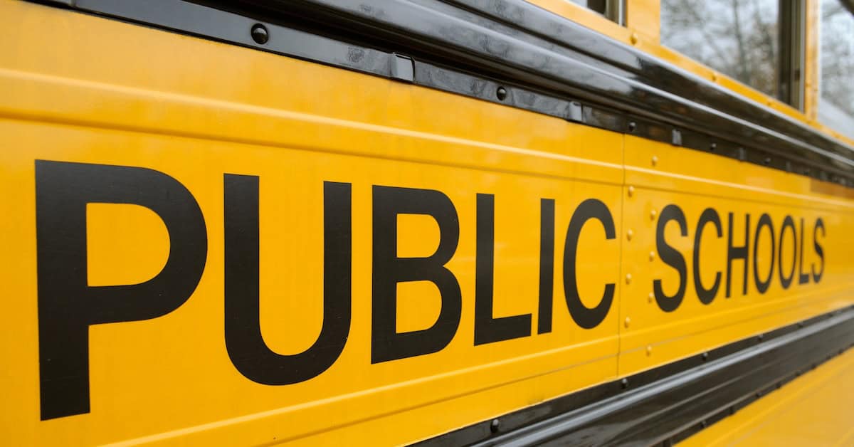 School bus exterior with "Public Schools" signage, yellow color, transportation for students, educational infrastructure, safety and community education, America Out Loud News.