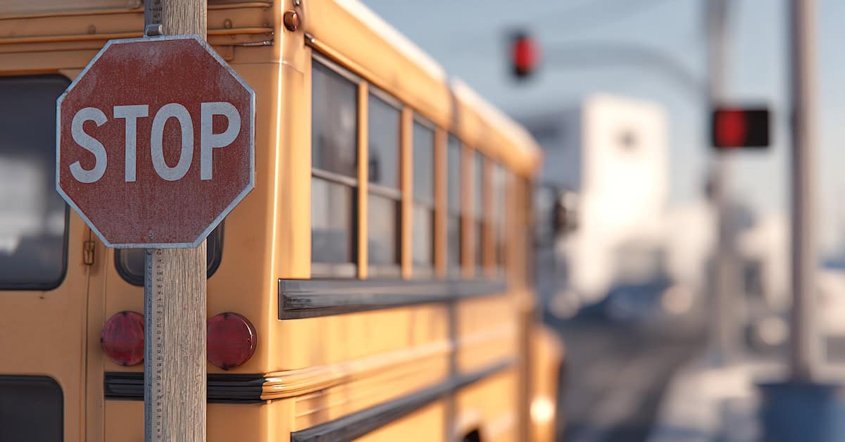 School bus stops at a traffic signal with a stop sign during the day in a residential neighborhood