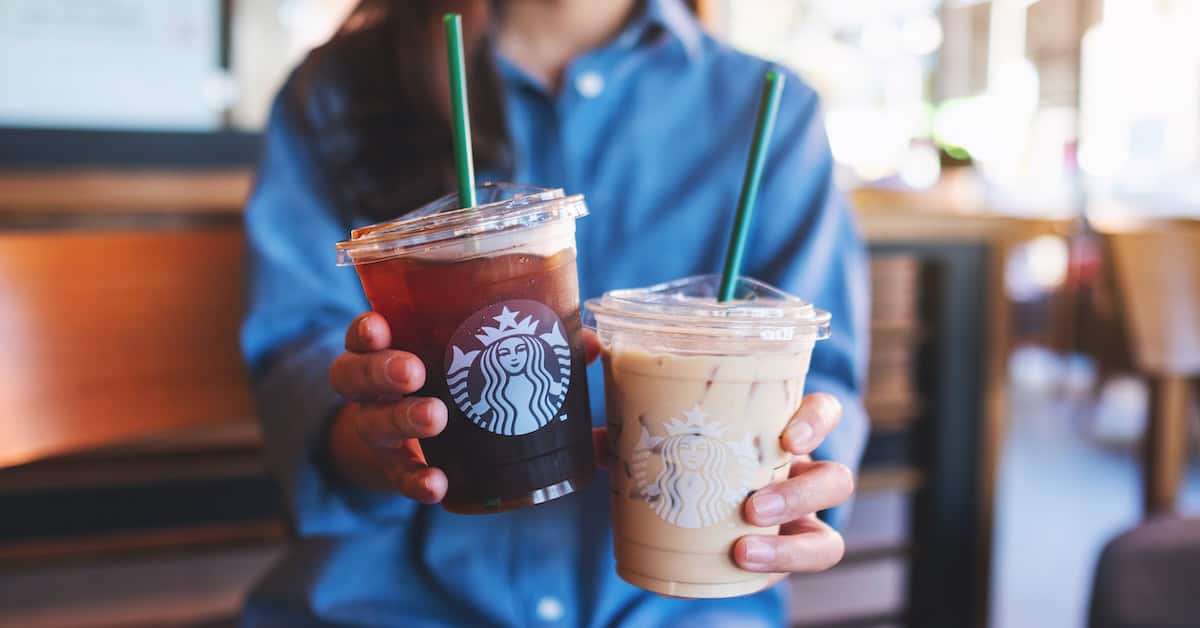 Jan 25th 2022 : Closeup of a woman holding or serving two glasses of iced coffee at Starbucks coffee shop, Chiang mai Thailand