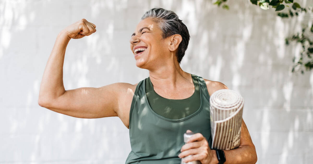 Elderly woman celebrates her fitness achievements by flaunting her bicep outdoors
